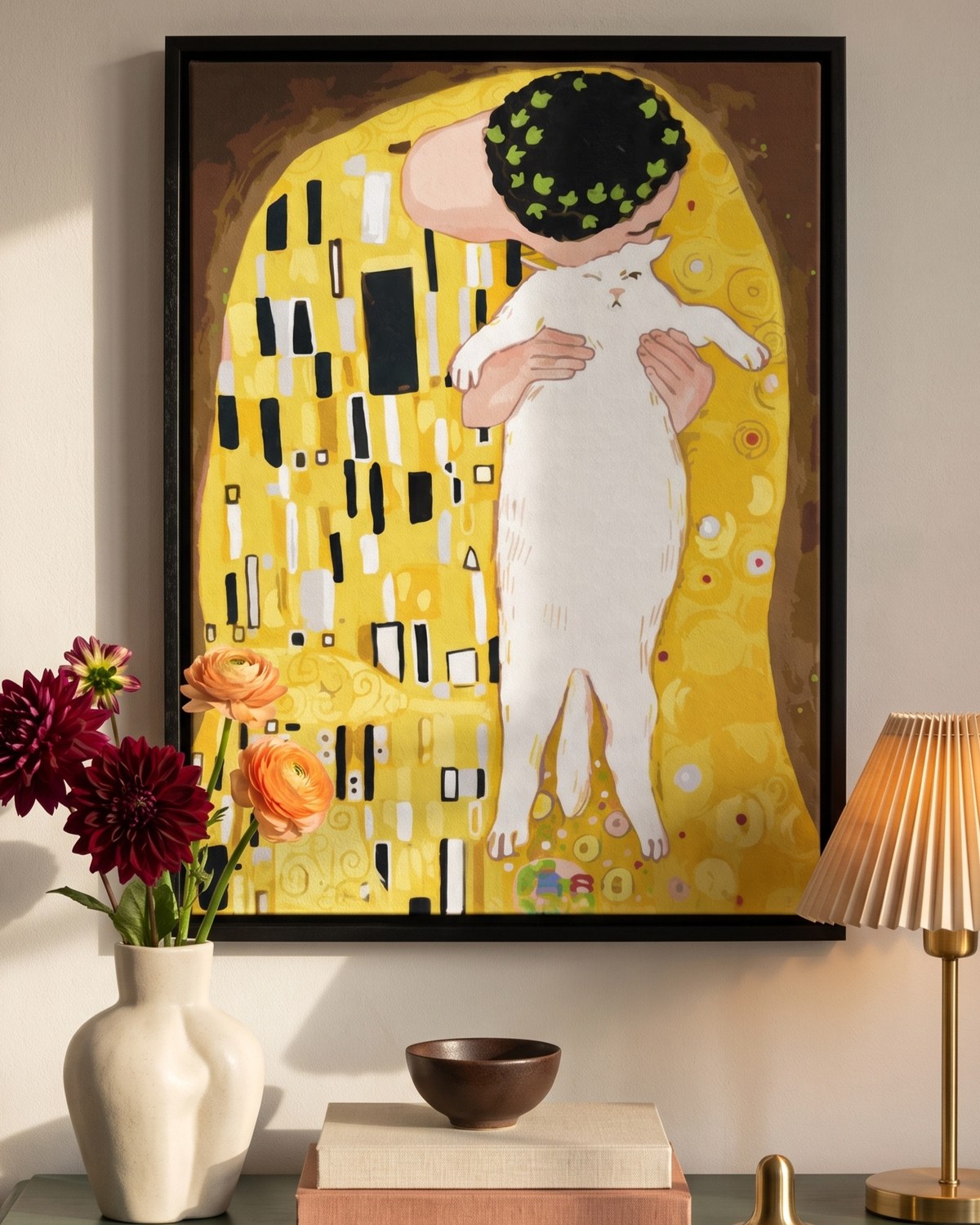 A Klimt inspired cat and owner painting as a stretched canvas in a black float frame, hanging above a green sideboard with dahlias.