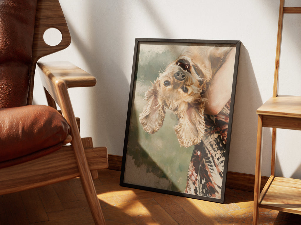 Flip by Muse and Paw, a painterly print of a cocker spaniel held upside down by its owner, styled in a sunlit room with a leather armchair and wooden chairs.