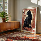 Her Majesty black cat playing card wall art in a pale frame, leaning against a wall beside a walnut sideboard and a patterned rug.