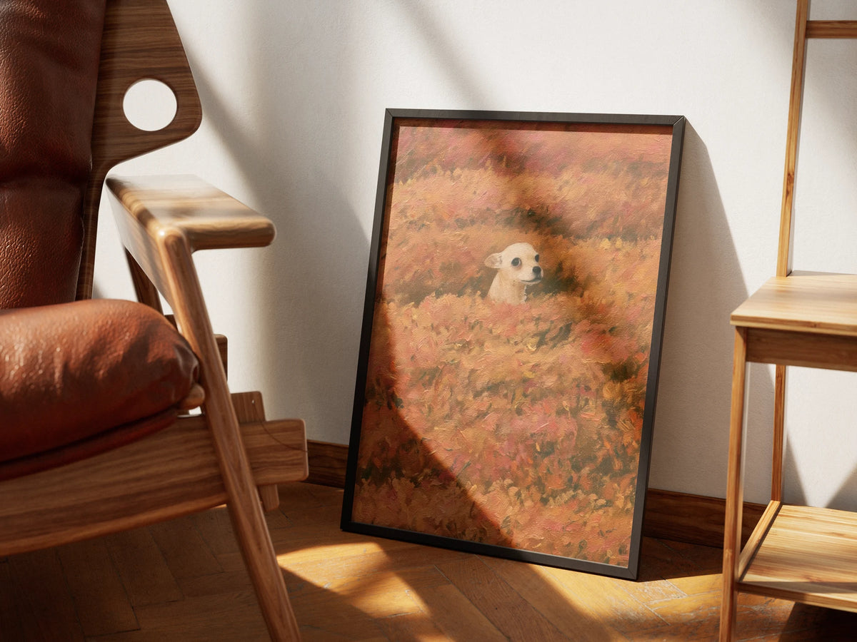 Hide and Seek by Muse and Paw, a print of a small chihuahua peeking out of a field of orange autumn flowers, framed and styled in a sunlit room with a leather armchair and wooden shelving.