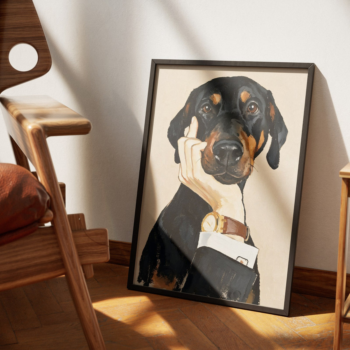 Hush by Muse and Paw, a painterly print of a black and tan dog with a human hand raised to his muzzle against warm cream, framed and leaning against a wall.