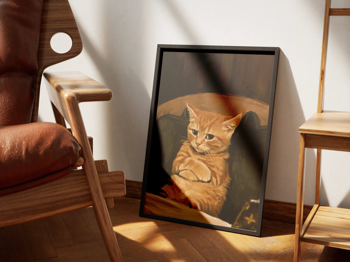 Not Amused by Muse and Paw, a print of a ginger tabby cat with folded arms sulking in a dark armchair, framed and styled in a sunlit room with a leather armchair and wooden shelving.