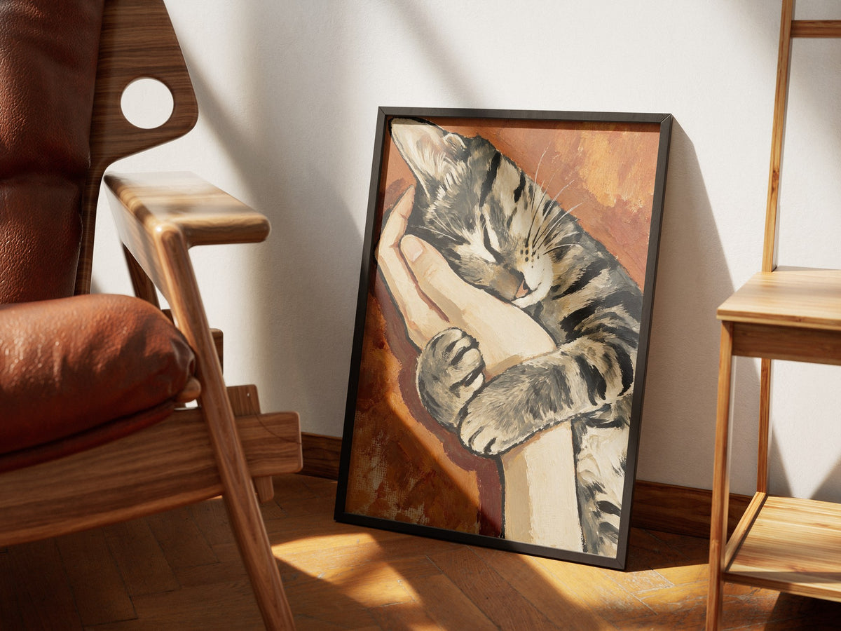 Safe sleeping tabby cat wall art framed in black, styled in a sunlit room with a walnut chair and oak shelving.