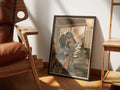 Tea Break by Muse and Paw, a print of a dachshund in a kimono and round glasses holding a cup of tea, framed and leaning against a sunlit wall beside a leather chair and wooden shelving.